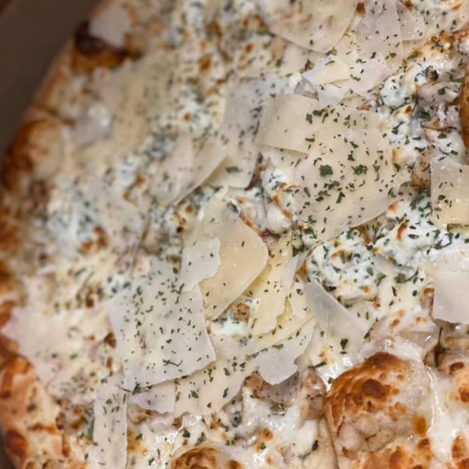Close-up of a Mamma Mineo's white pizza with ricotta, parmesan shavings, and dried herbs.