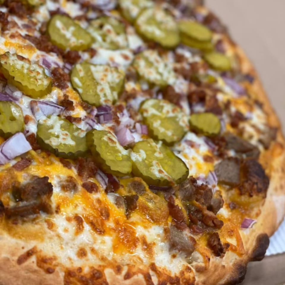 Close-up of a Mamma Mineo's pizza topped with pickles, red onions, and ground meat.